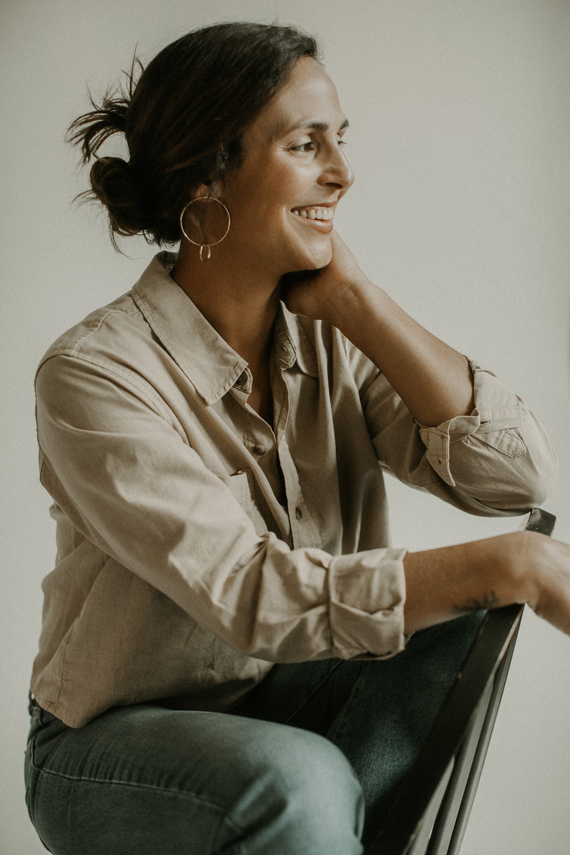 Solstice Naturals Owner Marisa Bello sitting with one hand on her chin against a plain background
