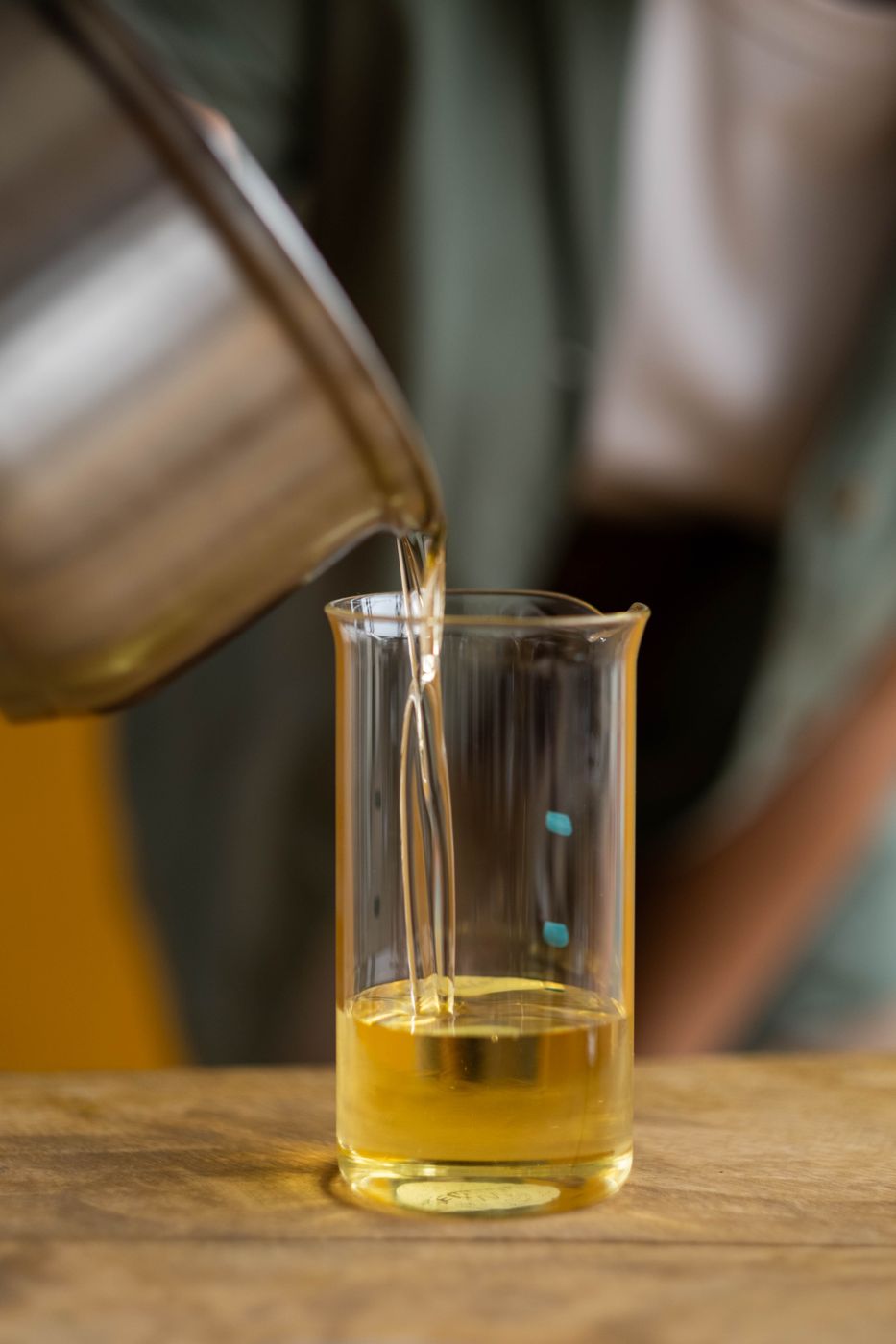 Golden melted candle wax being poured in an artisan candle-making workspace
